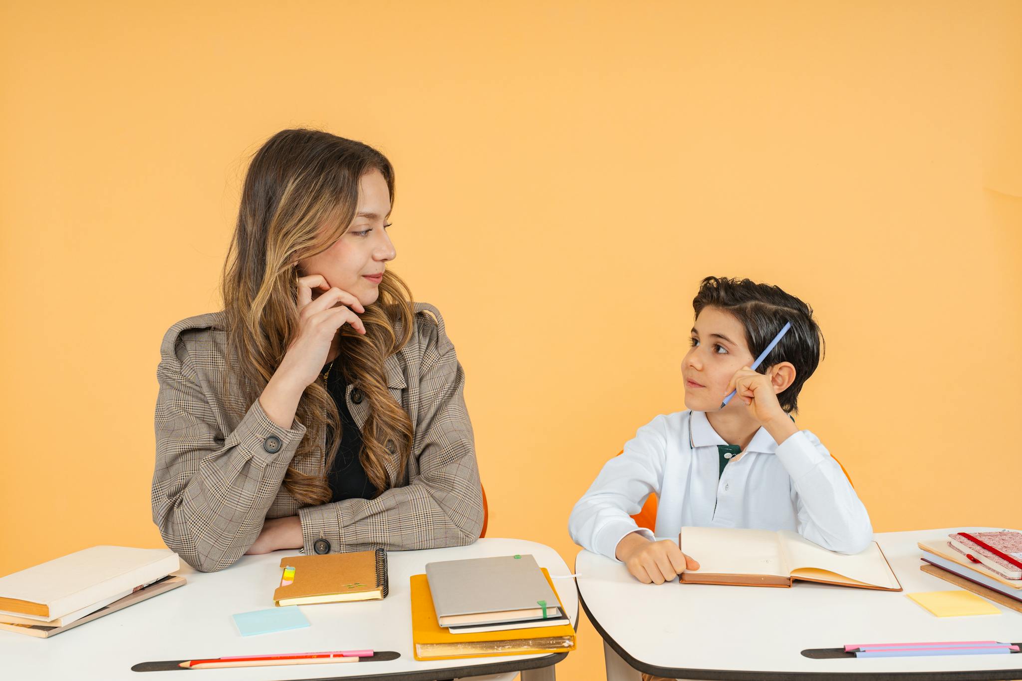 A teacher and student having an attentive discussion in a classroom setting with notebooks and pens.
